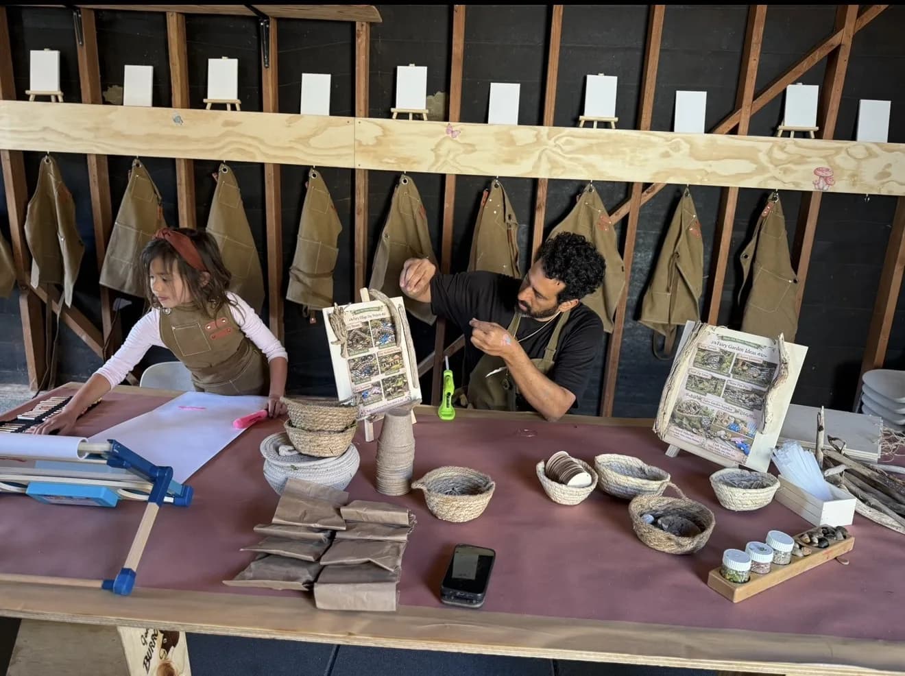 Children and a guide exploring natural materials at a prepared makers station